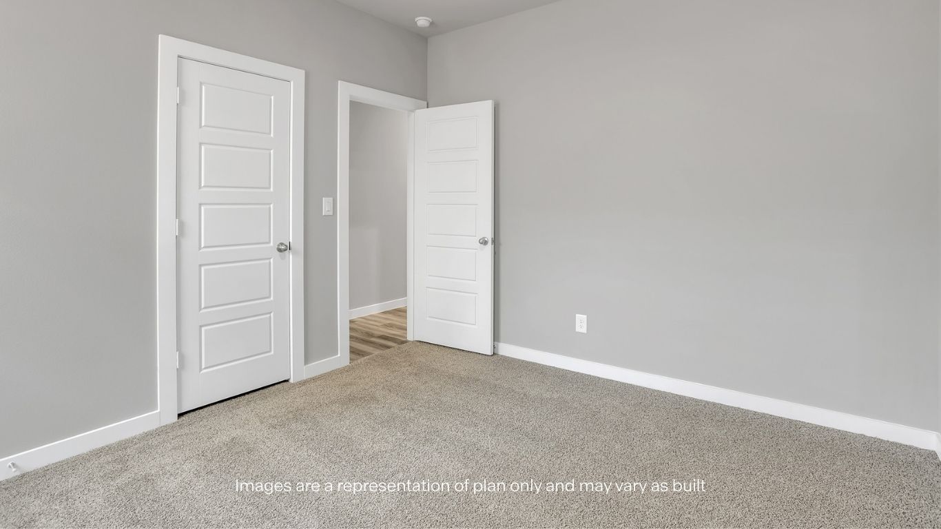 Another bedroom view showcasing neutral finishes, carpet flooring, and doorways for closet and hallway access.