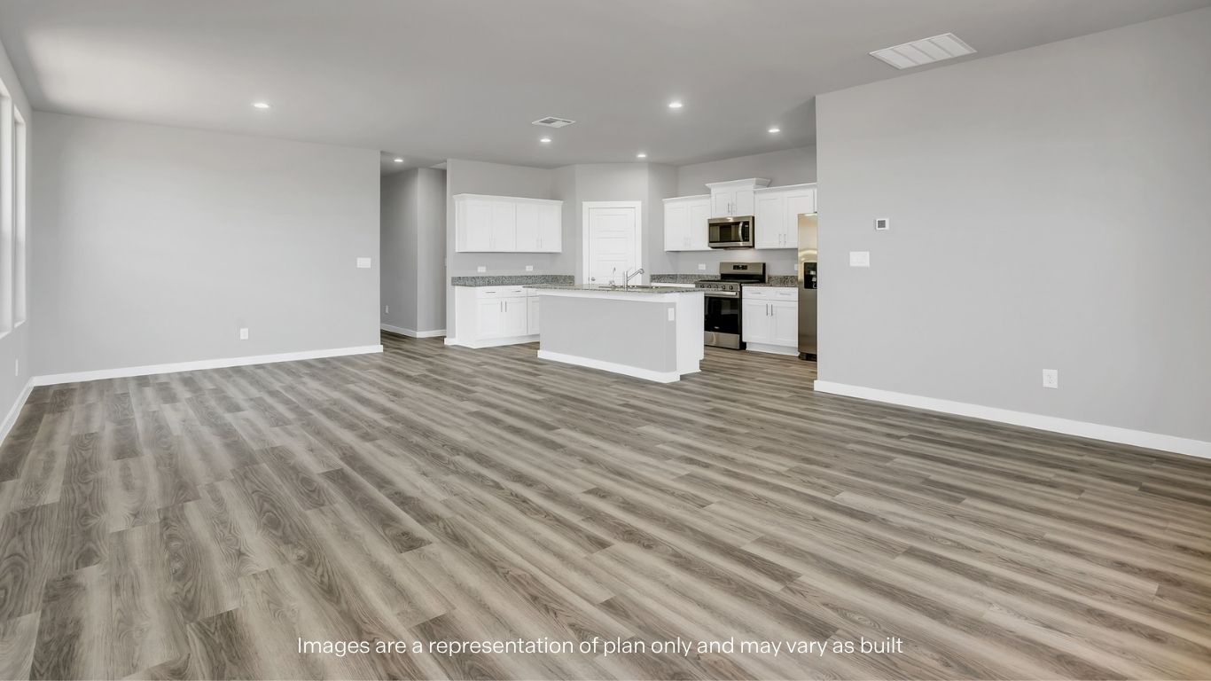 An open-concept living area connecting seamlessly to the kitchen with wide plank flooring.