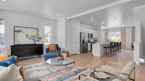 Modern open-concept living room, kitchen and stair entrance to upstairs.