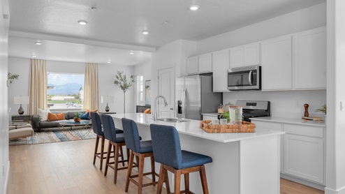 Kitchen with cabinets and island for bar stools and stainless steel appliances.