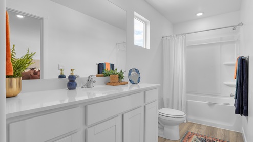 Primary bathroom with white cabinets and countertops and shower surround.