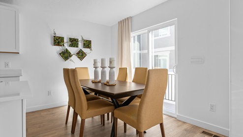 A spacious dining room with a 6 seat table and a sliding glass door to the patio.