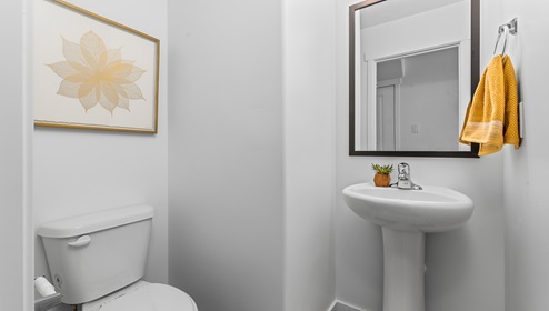 On the other side of the kitchen opposite the dining room and towards the garage entrance is the powder room with a pedestal sink.