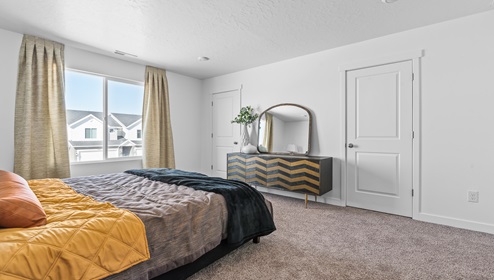 A view of the spacious primary bedroom as you look from the head of the large bed.