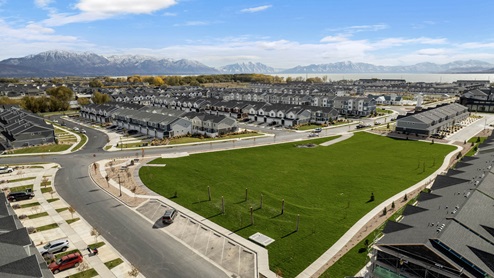Aerial view of the Northshore community and it’s rows of chic townhomes for sale in Saratoga Springs Utah with the backdrop of beautiful Utah Lake and the surrounding Uinta mountains.