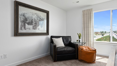 A view of the large sitting area in the primary suite next to a large window letting in beautiful light.