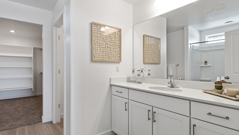 Primary suite bathroom at the Clover floor plan with a water closet and a large walk in closet with 3 walls of amazing built in shelving for organization.
