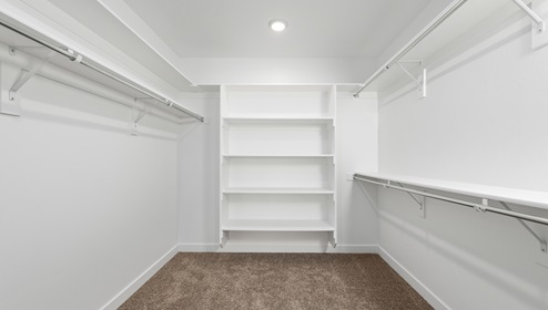 Full view of the Clover floor plan’s walk in closet with built in shelving on 3 large walls.