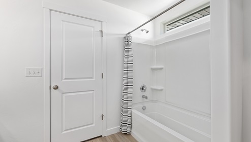 Full size bathroom with tub shower combination and window high and across the top.