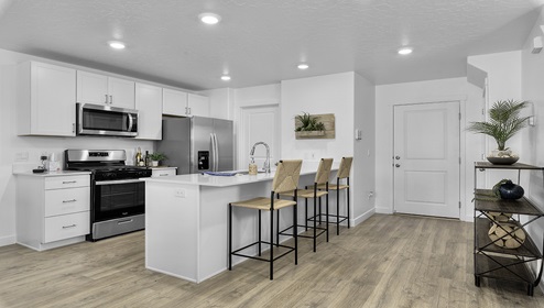 Kitchen space with peninsula featuring barstools, sink, kitchen cabinets, and appliances.