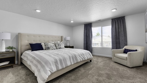 Primary bedroom with large window and three square windows above bed.