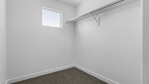 Spacious walk-in closet with square window off of bathroom.