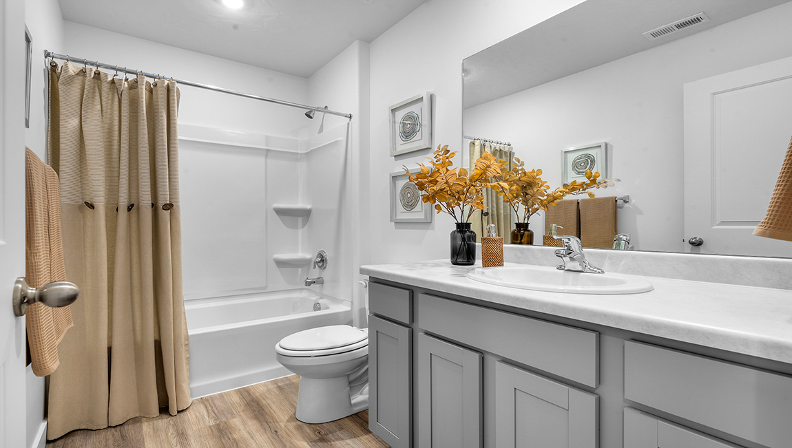 Full size bathroom with white shaker cabinets and a tub shower combination.