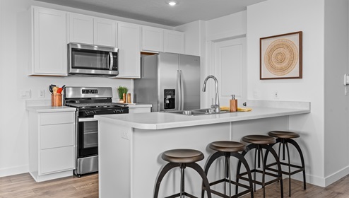 Kitchen with convenient peninsula with sink, white cabinets and stainless steel appliances.