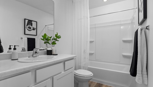 Full size bathroom with white cabinets and countertop, toilet and tub shower combination.