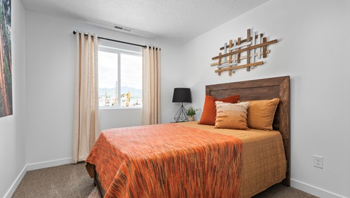 A stylish secondary bedroom with a large window in a townhome floor plan in Tooele Utah.
