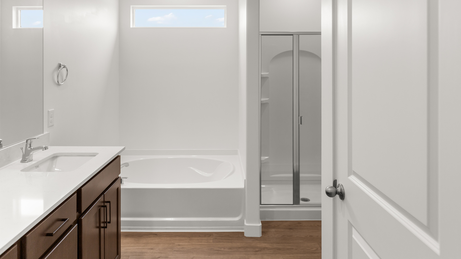 Primary bathroom with double sink vanity, bath and shower, and window above shower.