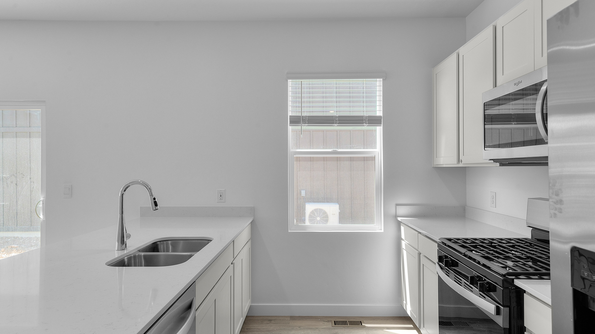 Kitchen with kitchen island and stainless steel appliances and with window.