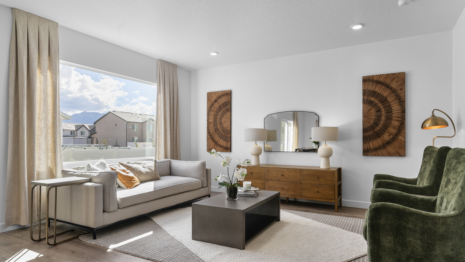 Open concept living space with living room with 2 windows on one wall and on the adjacent wall a very large window.