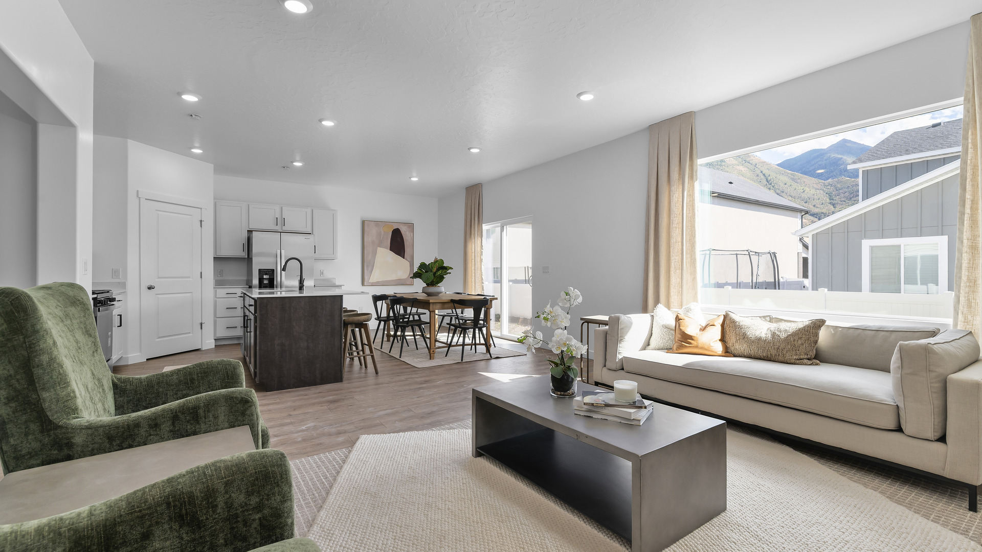 Open concept living space with living room with 2 windows on one wall and on the adjacent wall a very large window.