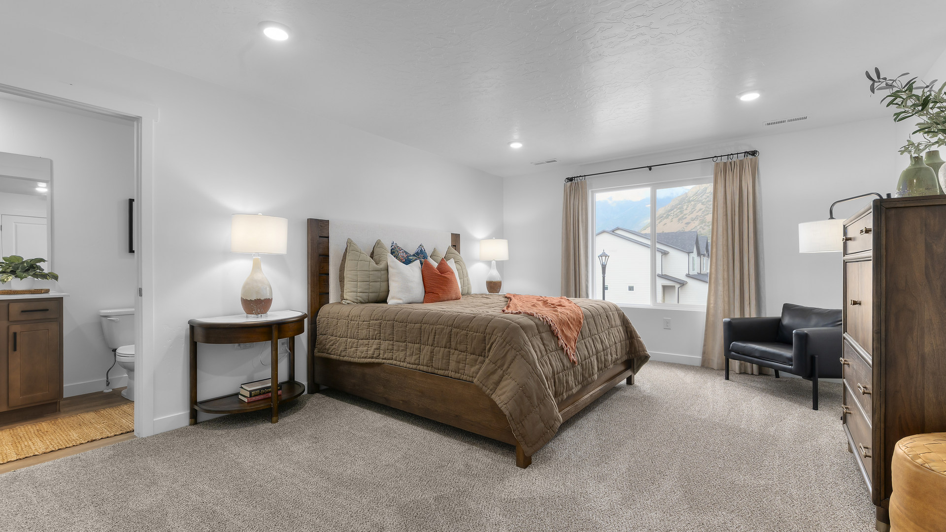 Spacious primary bedroom with a large window and door leading into the en suite full sized bathroom.