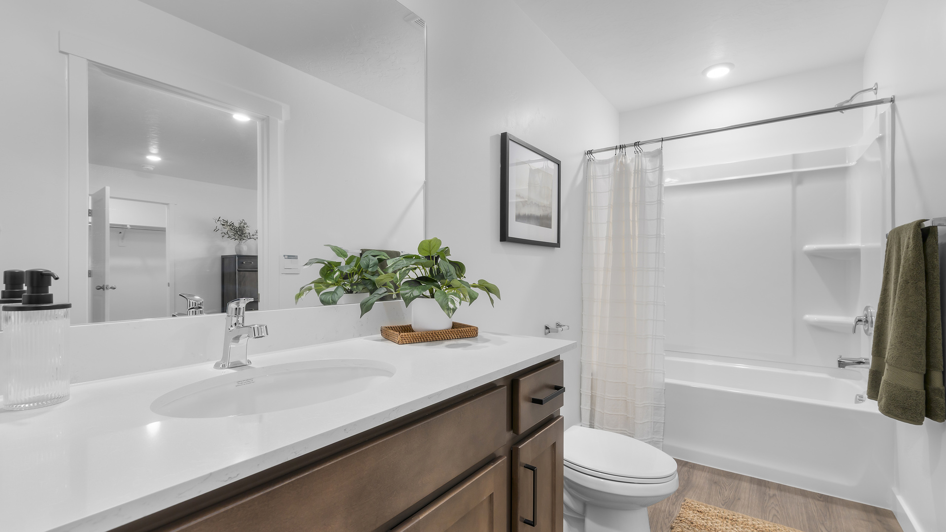 Primary bathroom with white cabinets and window above shower surround.