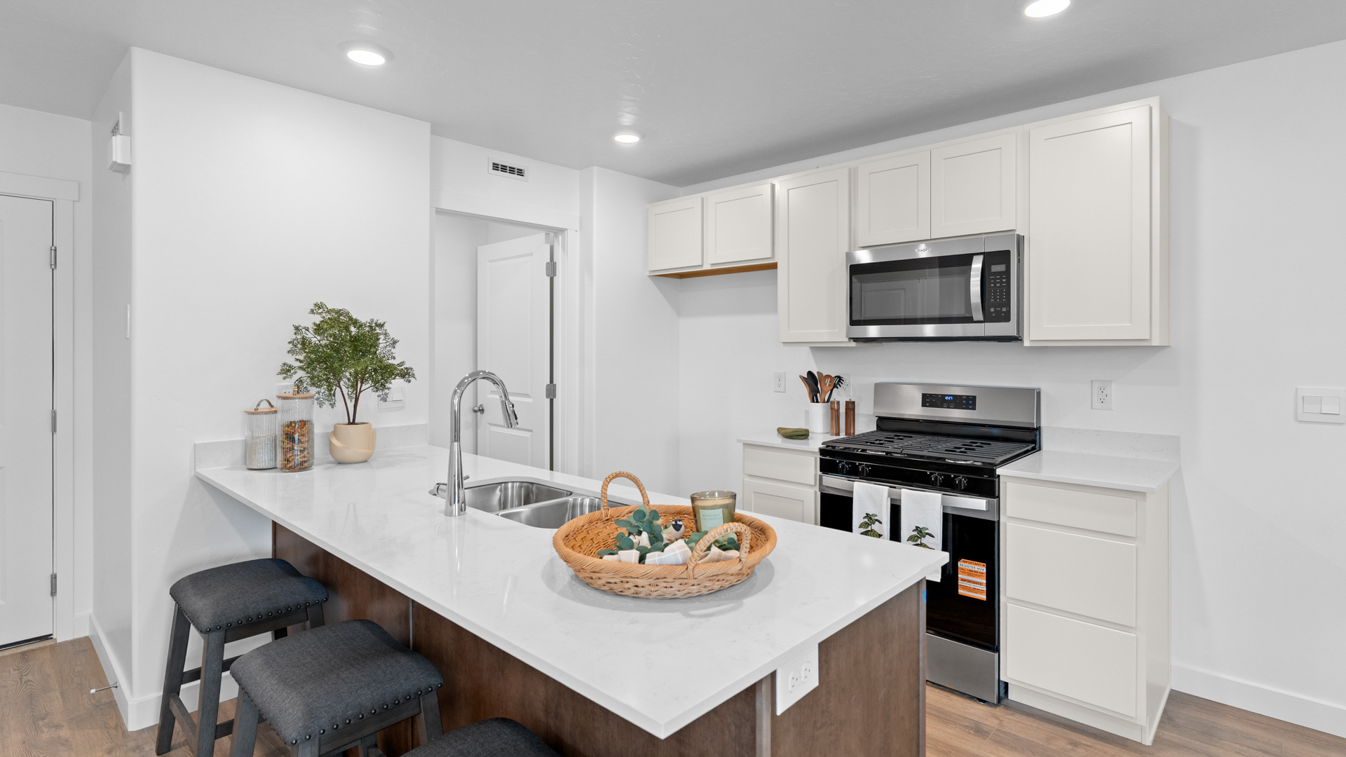 Kitchen space with peninsula featuring barstools, sink, kitchen cabinets, and appliances.