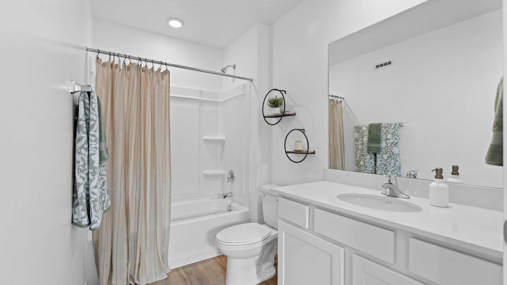 Bathroom with white cabinets and countertops and shower surround.