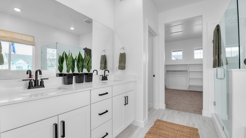 Primary bathroom with quartz countertops, dual sinks, water closet, walk in shower with glass door, and garden tub with large window above.