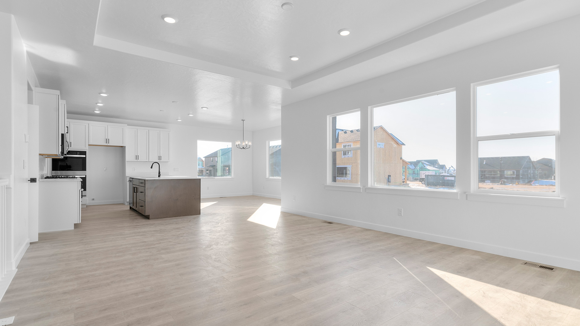 Main living area with large windows, tray ceiling, and kitchen area.