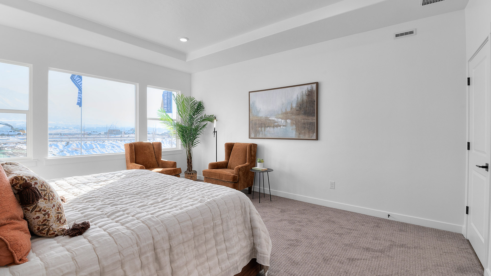 Primary bedroom with tray ceiling, recessed lighting, and large picture window.