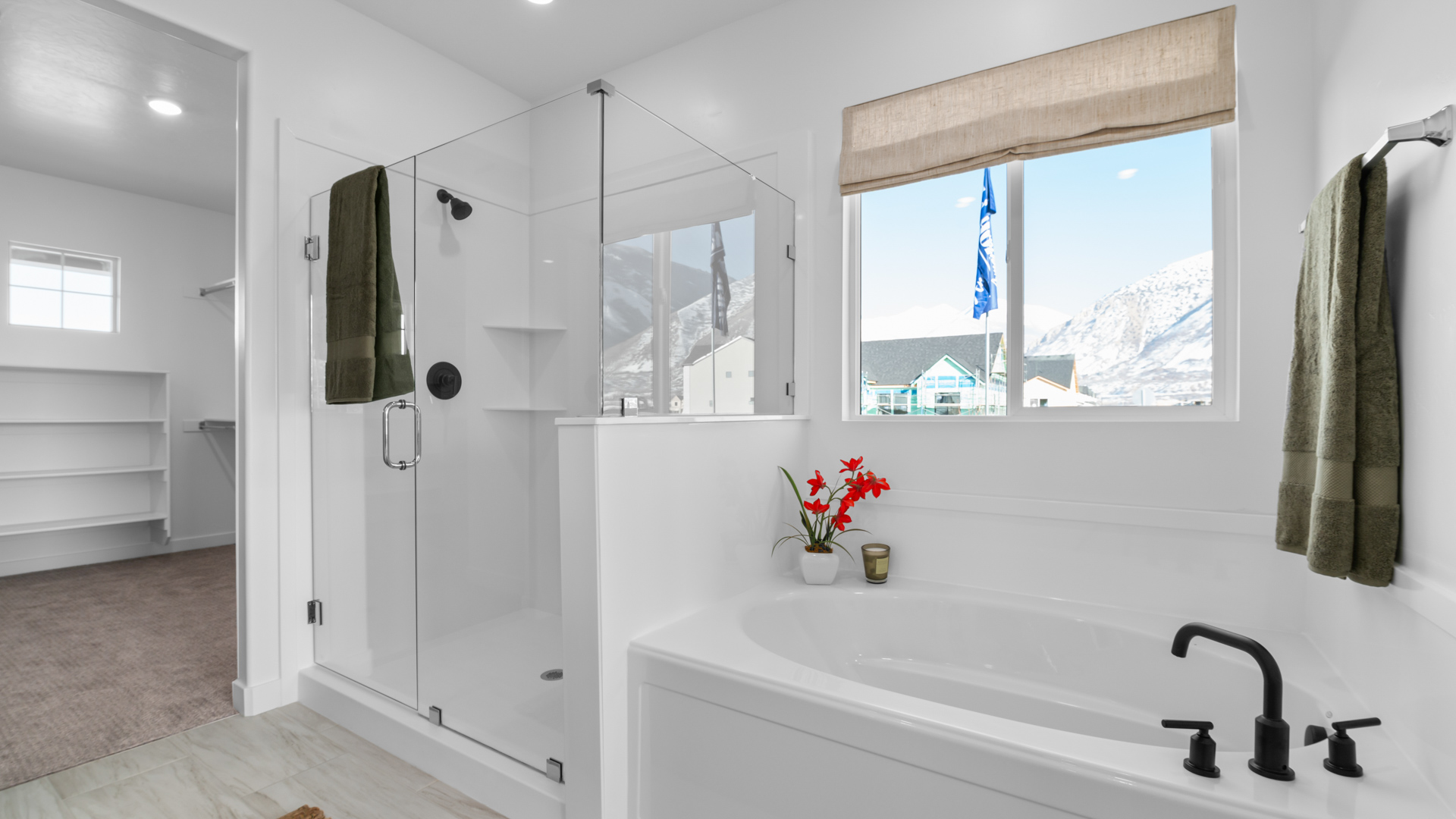 Primary bathroom with quartz countertops, dual sinks, water closet, walk in shower with glass door, and garden tub with large window above.