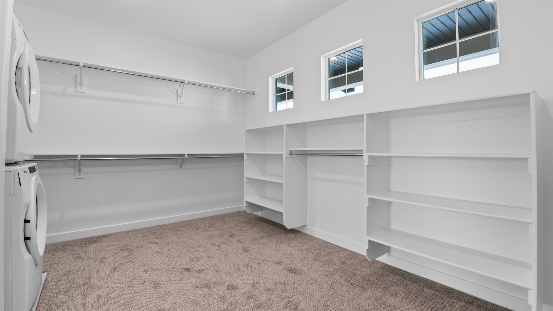 Primary closet with built in shelving and three windows for natural light
