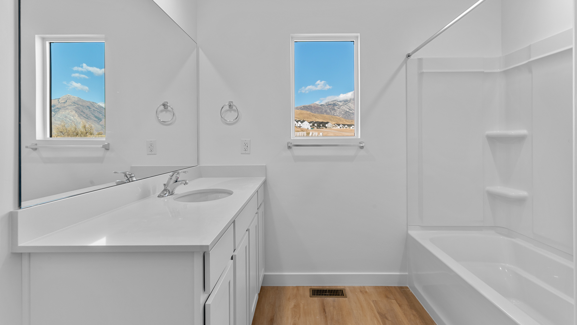 Primary bathroom with vanity and shower surround and window.