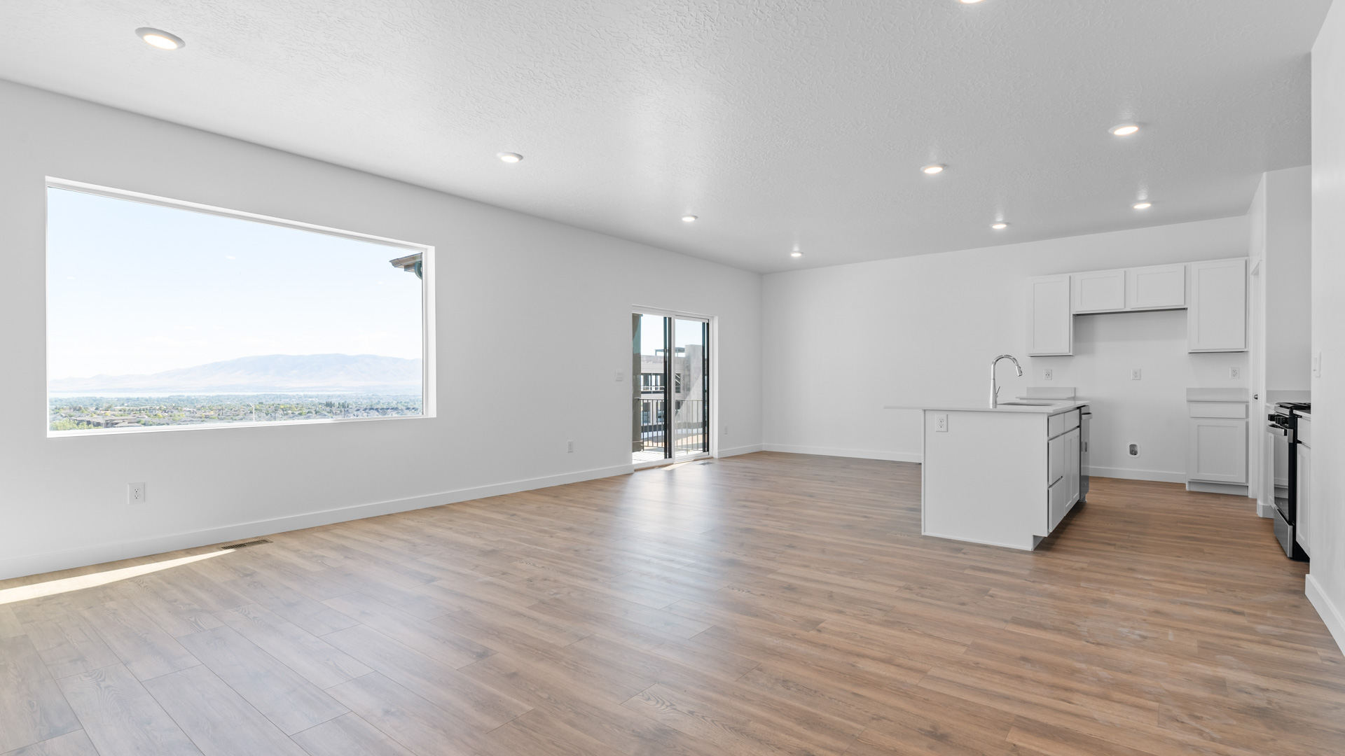 Main living space with large window, patio doors, kitchen, dining, living room.