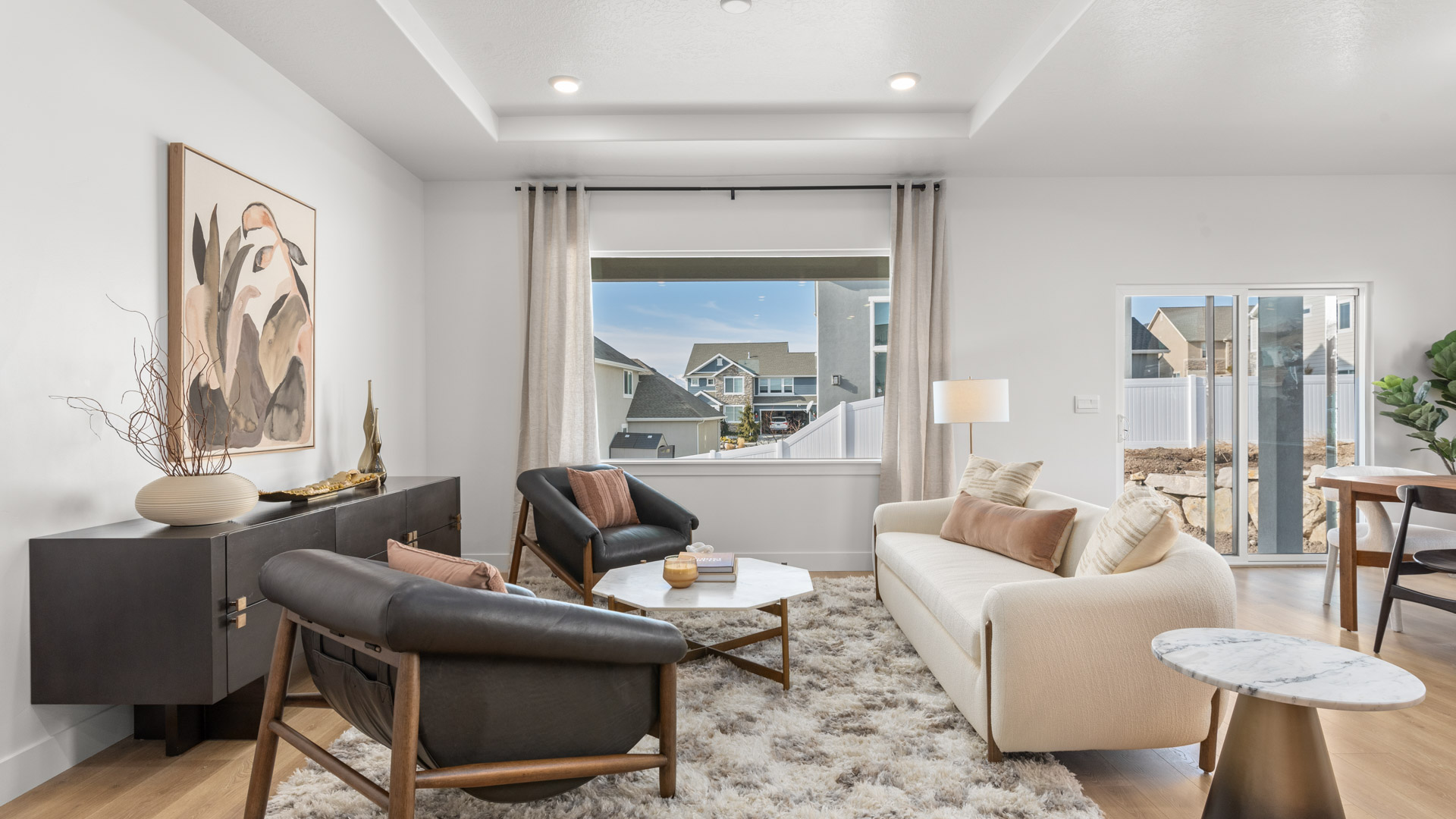 Spacious living room with large window and tray ceilings.