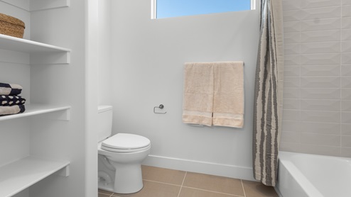 Water closet space with window, shelving, and shower.