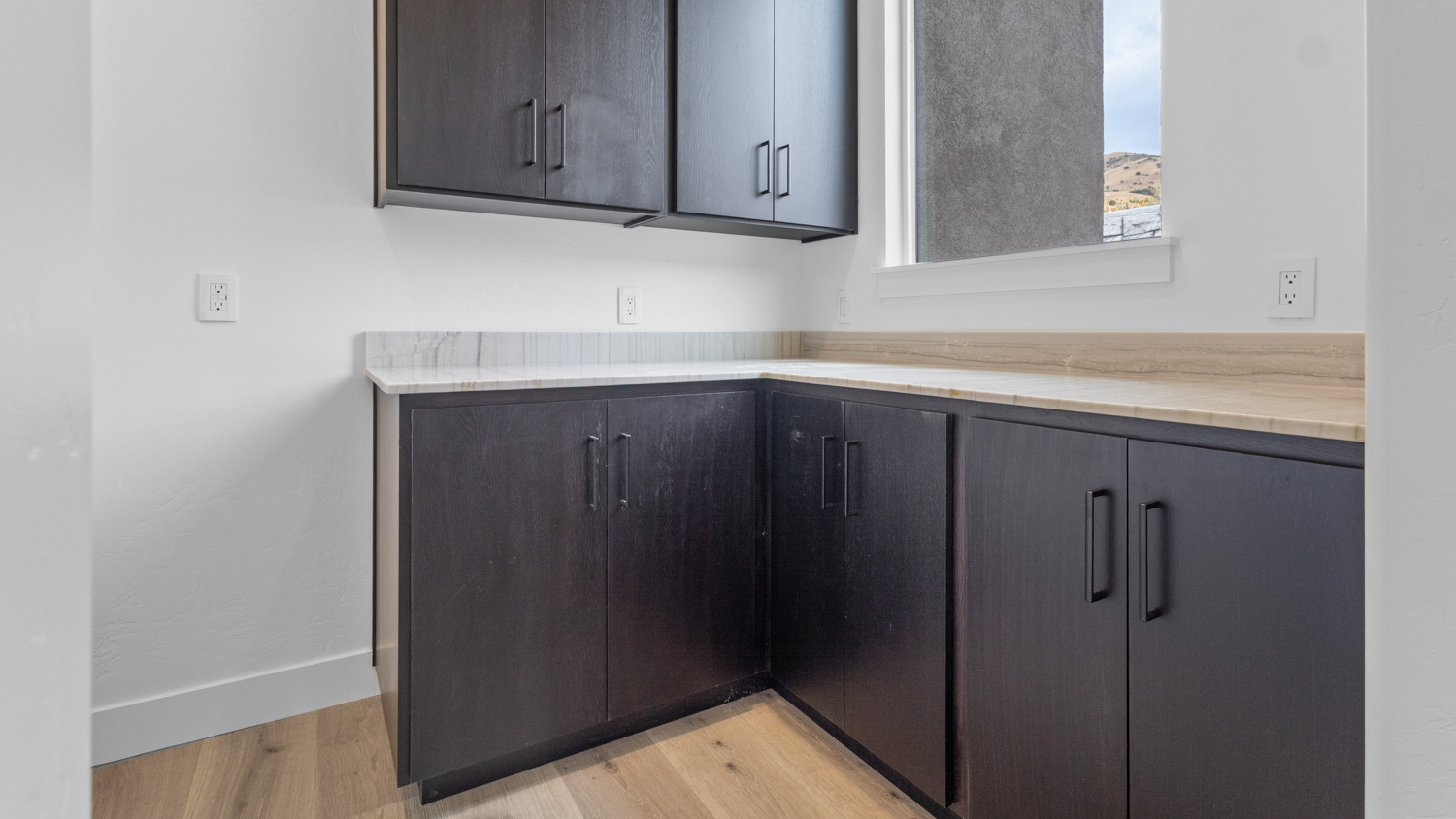 Butler pantry with window, shelving, and cabinets.