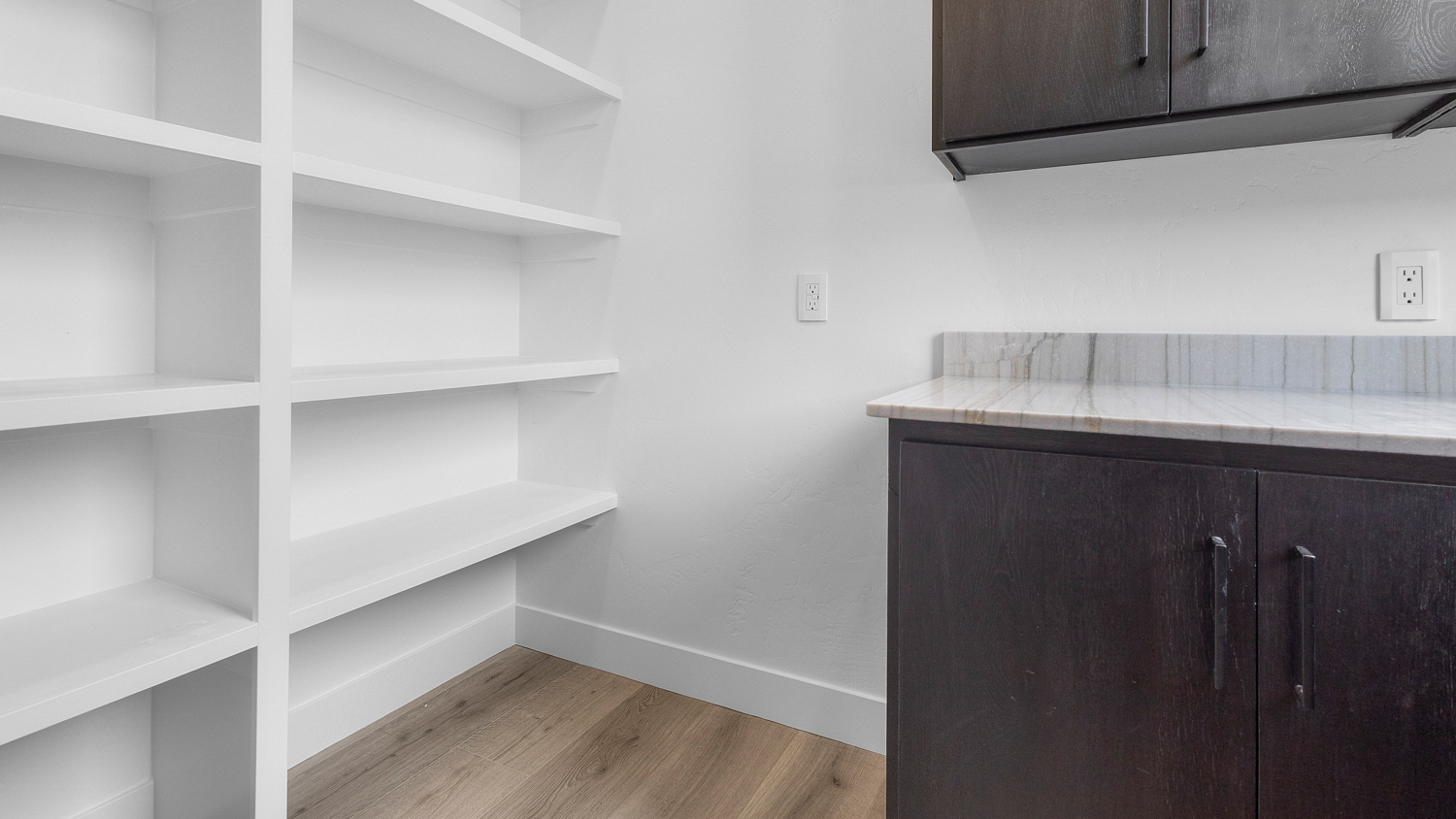 Butler pantry with window, shelving, and cabinets.