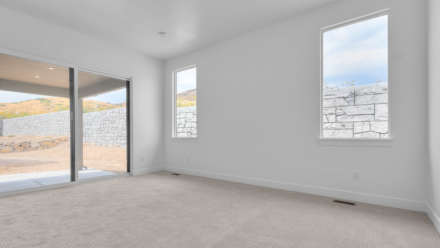 Primary bedroom with windows and glass patio doors.