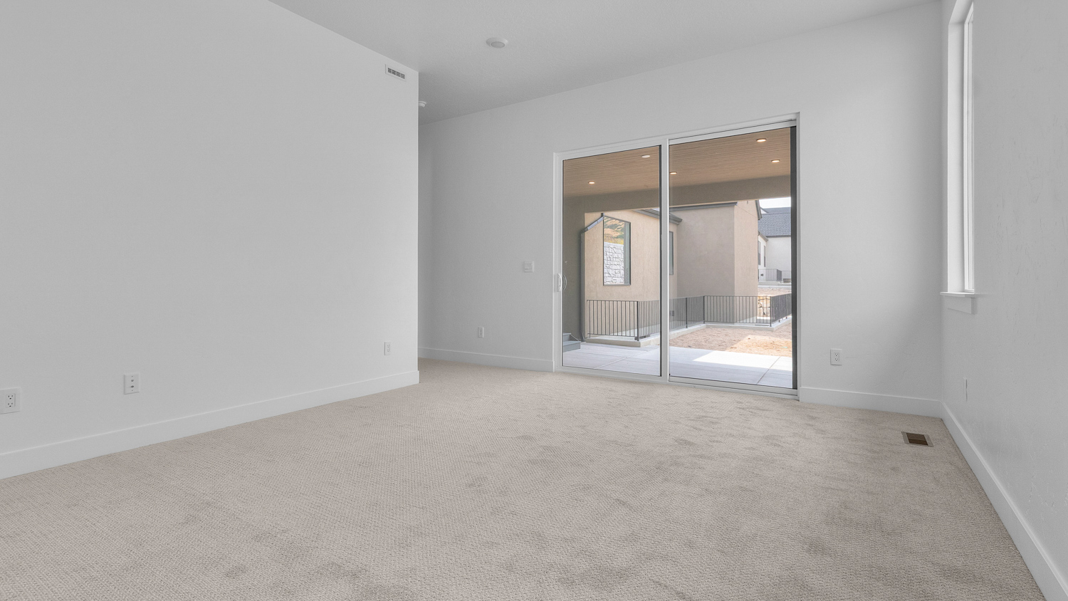 Primary bedroom with windows and glass patio doors.