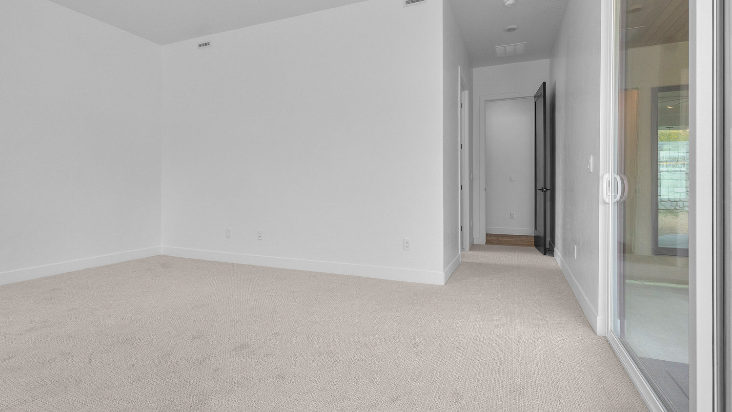 Primary bedroom with windows and glass patio doors.