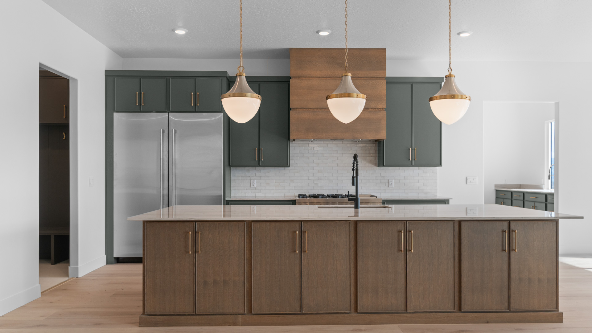 Kitchen with two toned cabinets, pendant lights, kitchen island with sink.