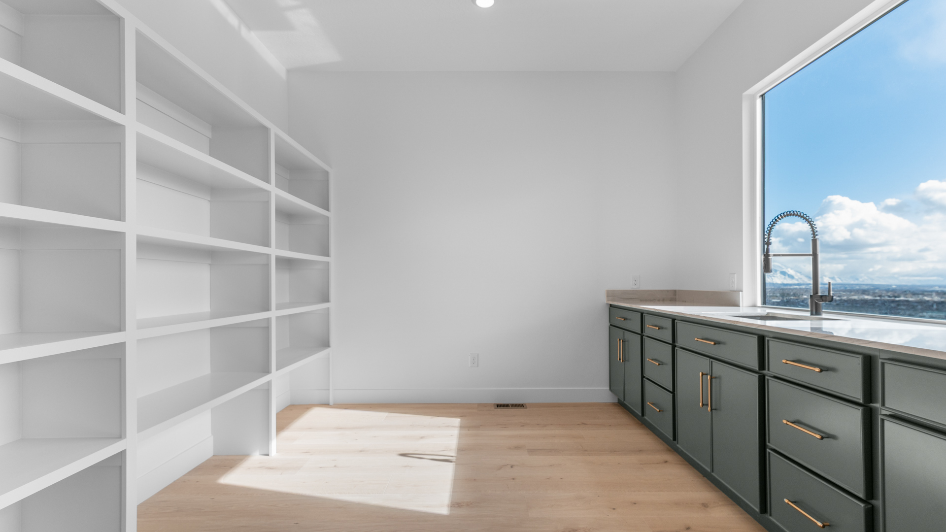 Butler pantry with shelving and countertop with cabinets and large window.