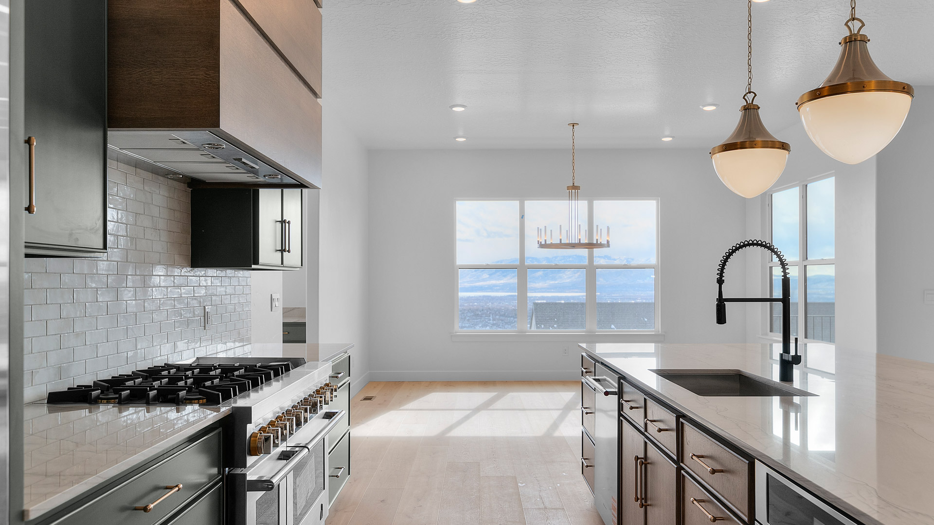 Kitchen with two toned cabinets, pendant lights, kitchen island with sink.