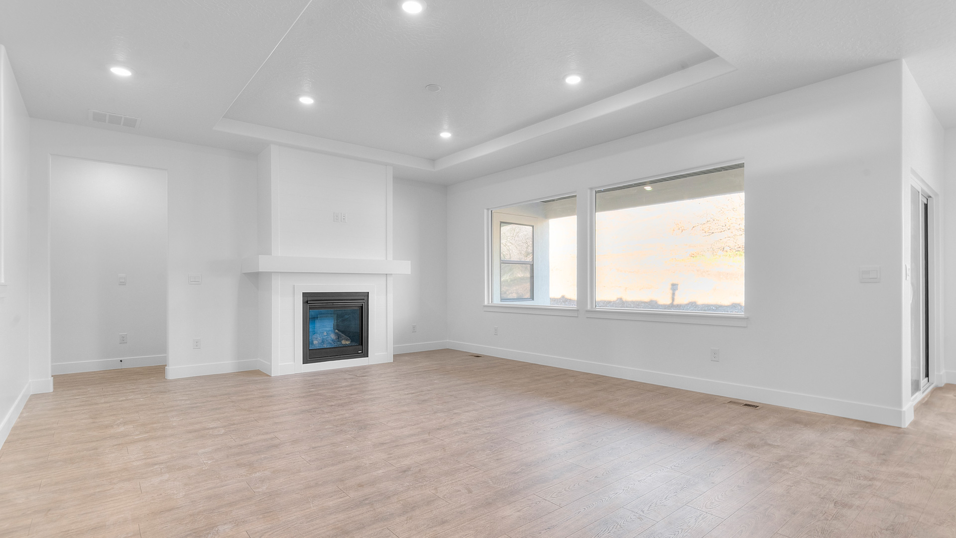 Family room with tray ceiling, fireplace, and large windows.
