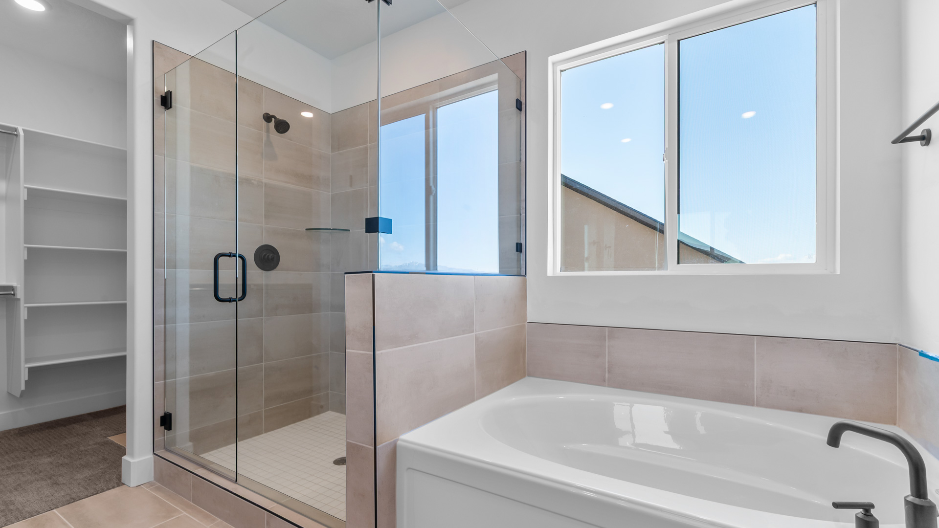 Primary bathroom with glass shower and tub with window.