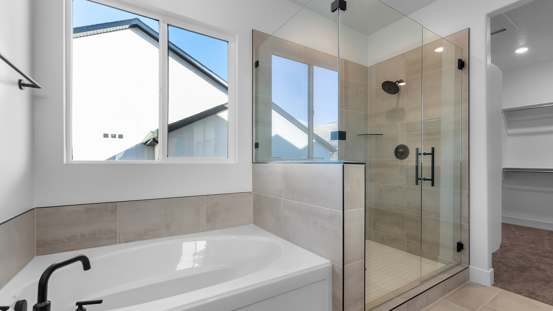 Soaking tub and glass shower with large window.