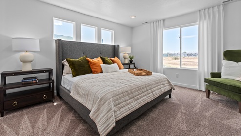 Primary bedroom with large window and three square windows above bed.