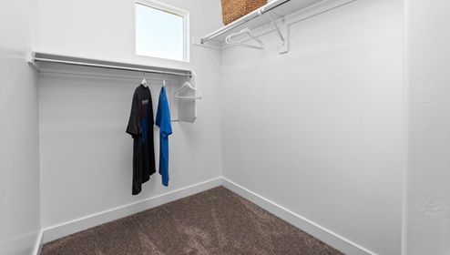 Spacious walk-in closet with square window off of bathroom.